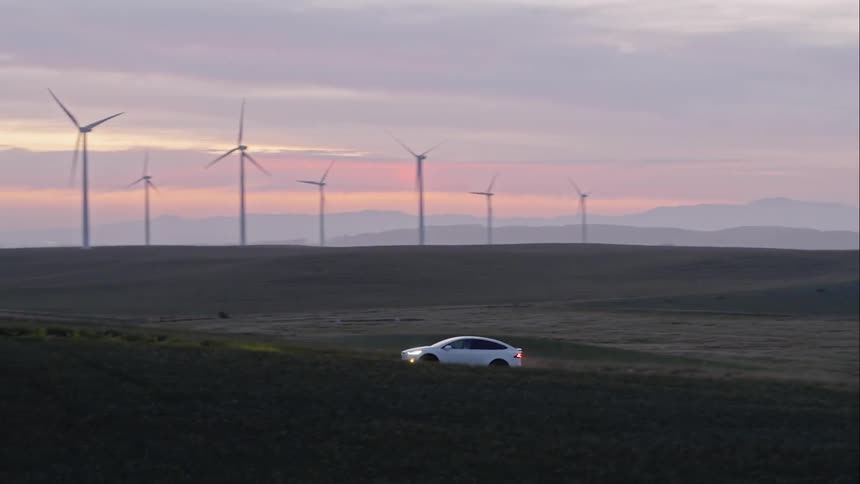 A car is driving in a rural area at sunset