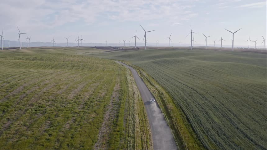 Car driving on road through wind farm