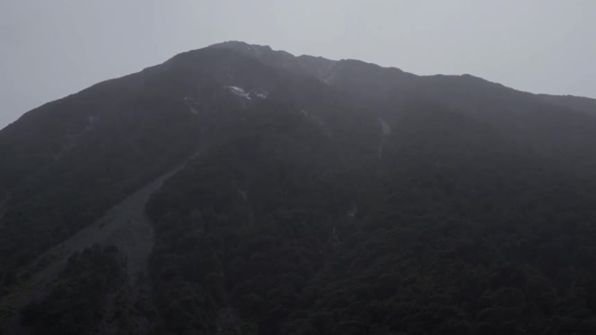 A mountain stands in the distance while it rains
