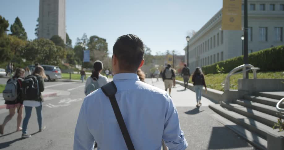 A man walks down a road on a collage capmus