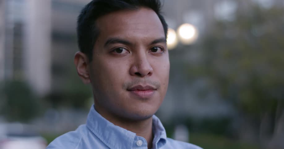 A man stands and stares into the distance before turning his head and smiling