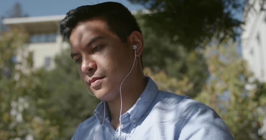Male looks at papers while having earbuds in his ears