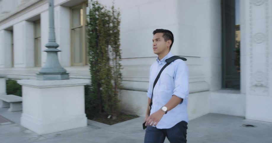 A man walks out of a large building on campus