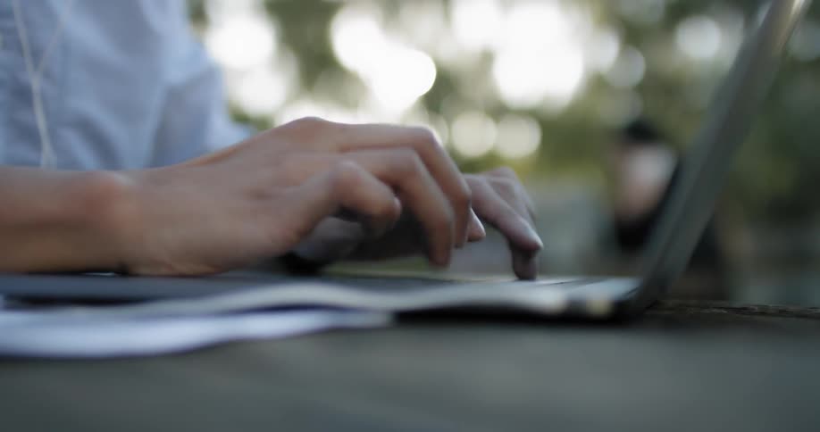 Man typing on laptop outdoors