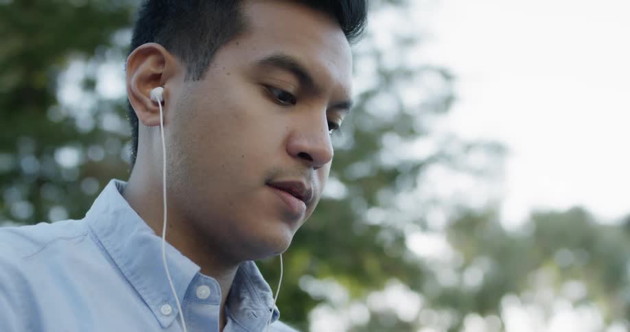 A man is sitting outside wearing headphones