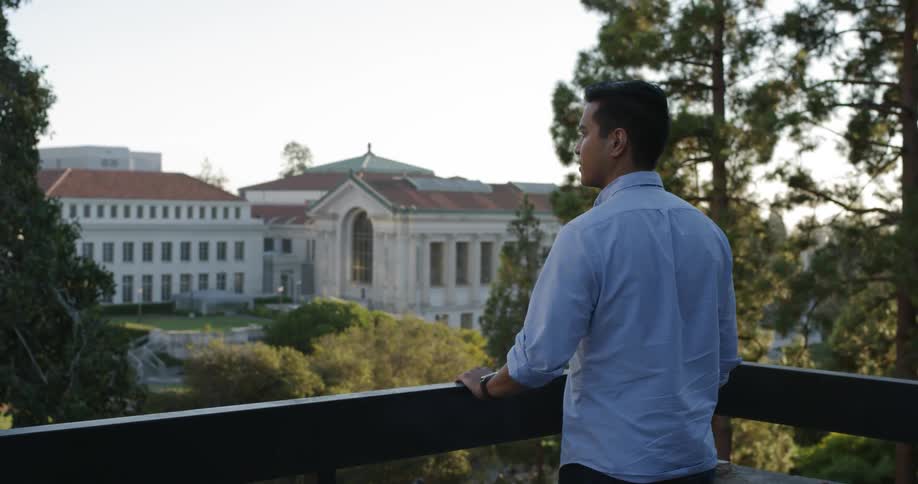 A man stands on a balcony and looks toward the view