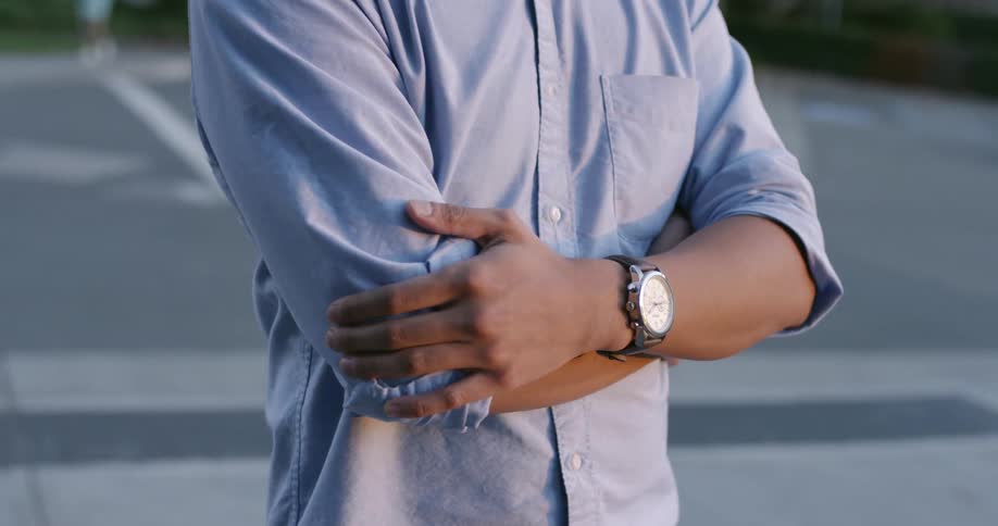 Man standing on a parking lot with his arms crossed on his chest