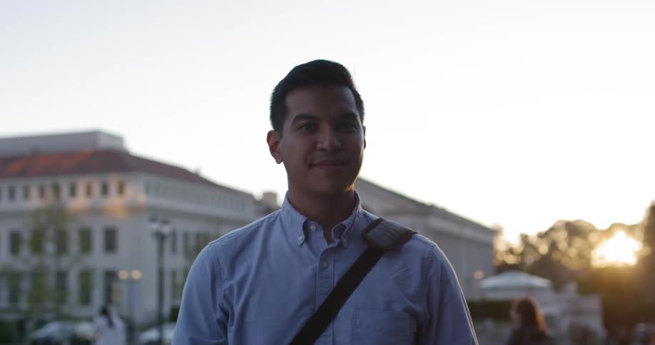 A man standing outside looking up turns his head and smiles
