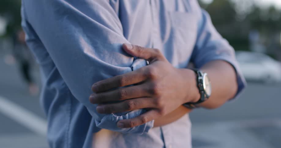Man stands outside in parking lot with his arms crossed