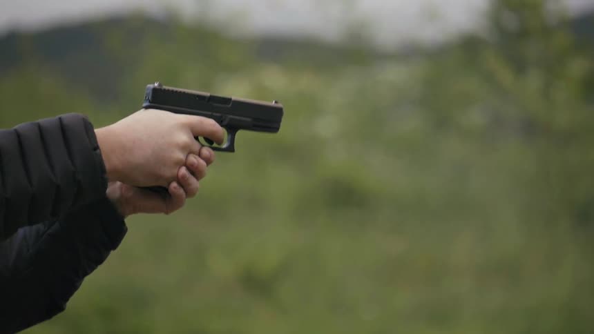 A person is firing a gun on a cloudy day