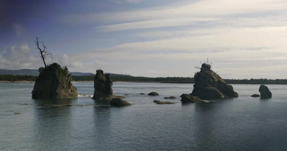 Water flows around three rocky outcroppings in a lake