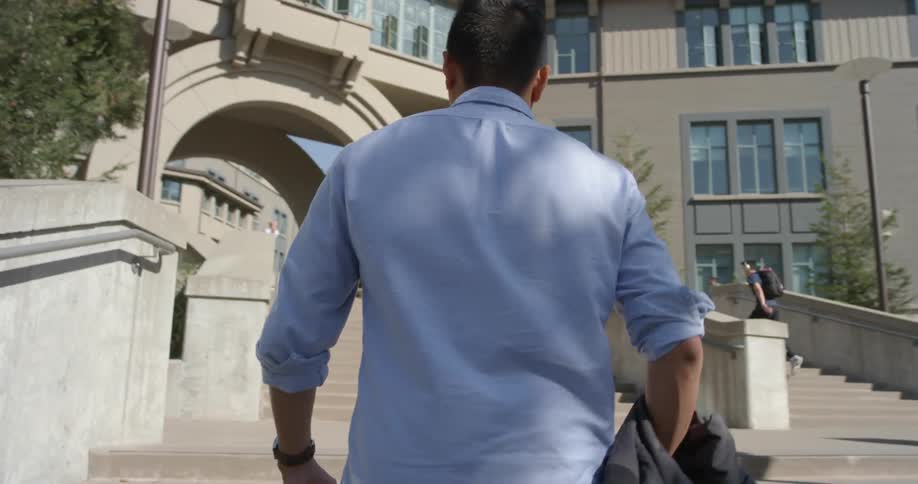 A man walks up stairs towards a building