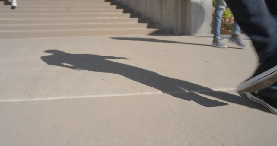 A boy wearing tennis shoes and blue jeans walks up some concrete stairs