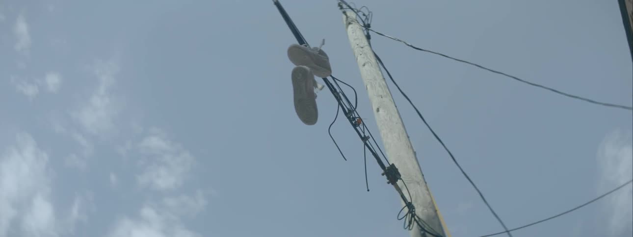 A pair of tennis shoes hangs off a power line on a sunny day