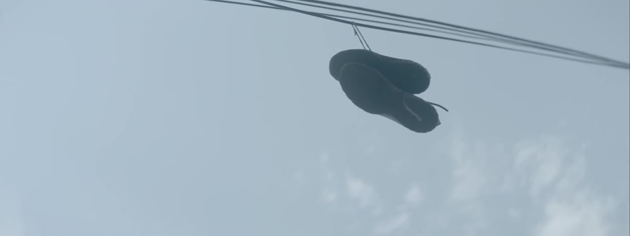 A pair of sneakers hanging from an electric line by its laces