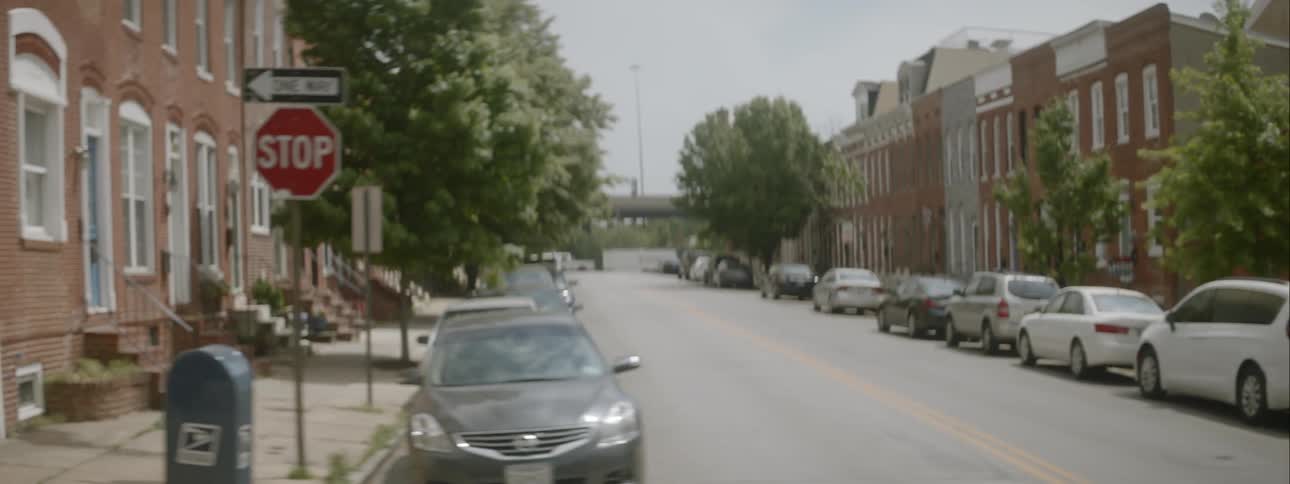 A two lane street lined with parked cars in a city neighborhood