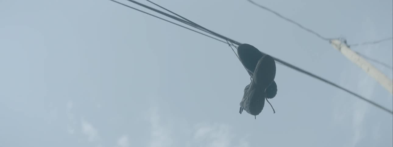 Tennis shoes tied to a power line outside of a house