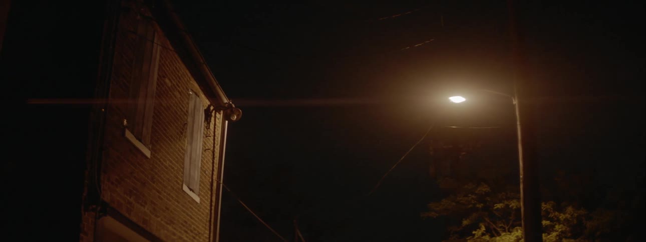 A lone street lamp burns outside a building at night