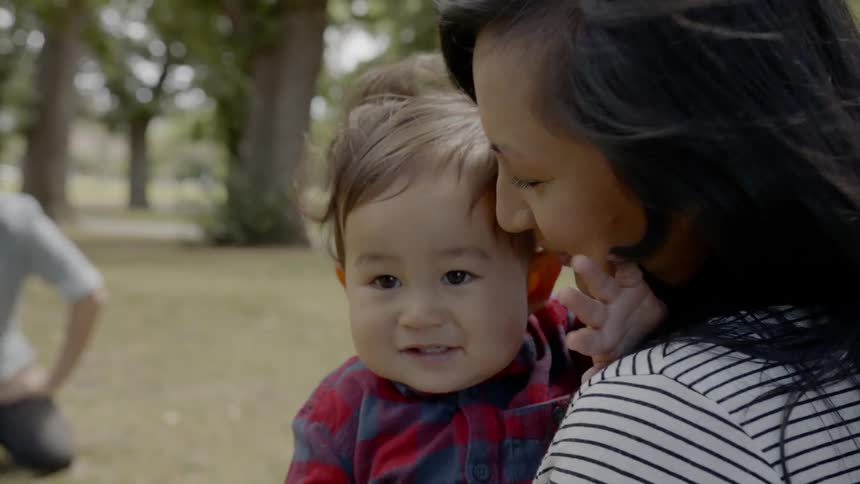 A woman holding a baby kisses it on the head