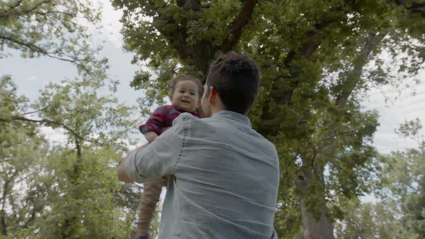 A man holding a small child in the air and spinning around playfully