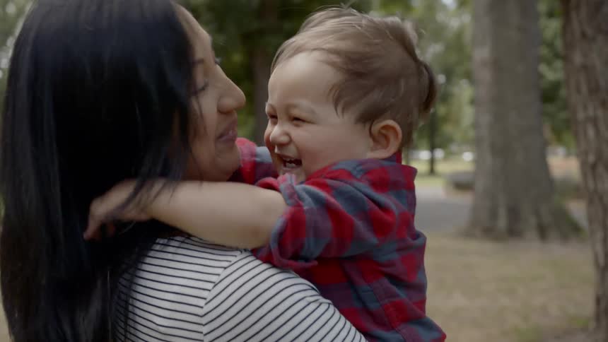 A woman holds a laughing baby
