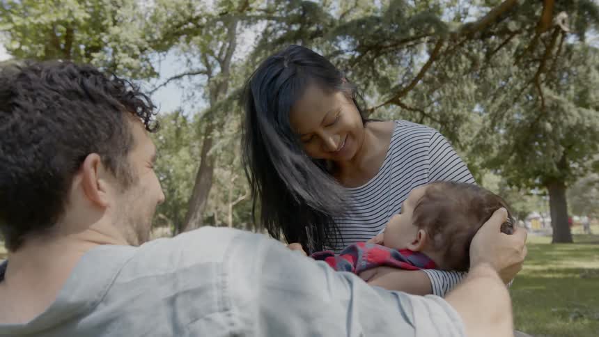 A man and woman caring for a toddler in a park
