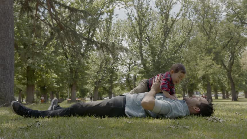 A father raises his son into the air in a park