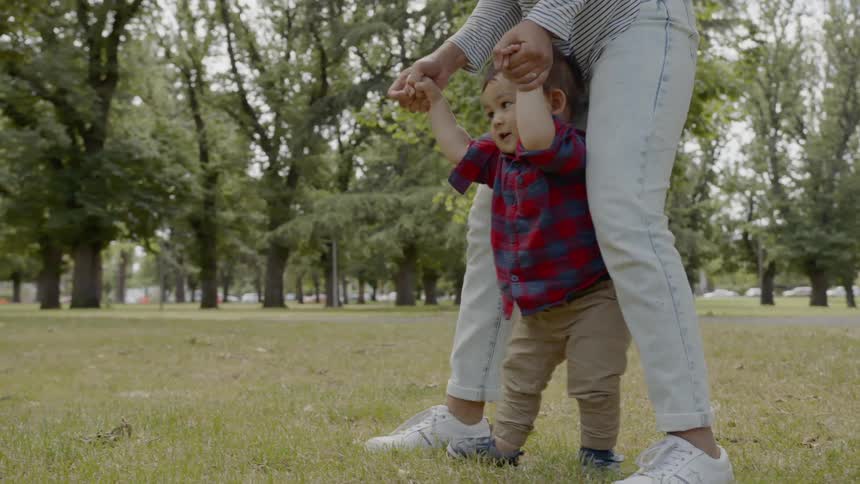 Mom helping son walk in the park