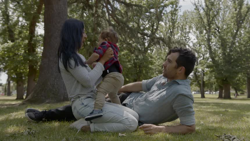 Parents and their child sit together in the grass