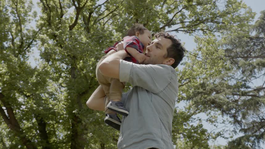 A father lifts his son into the air and then holds him to his chest