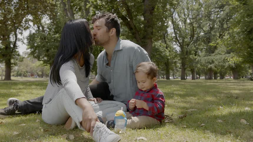 Father mother and son are sitting in the grass