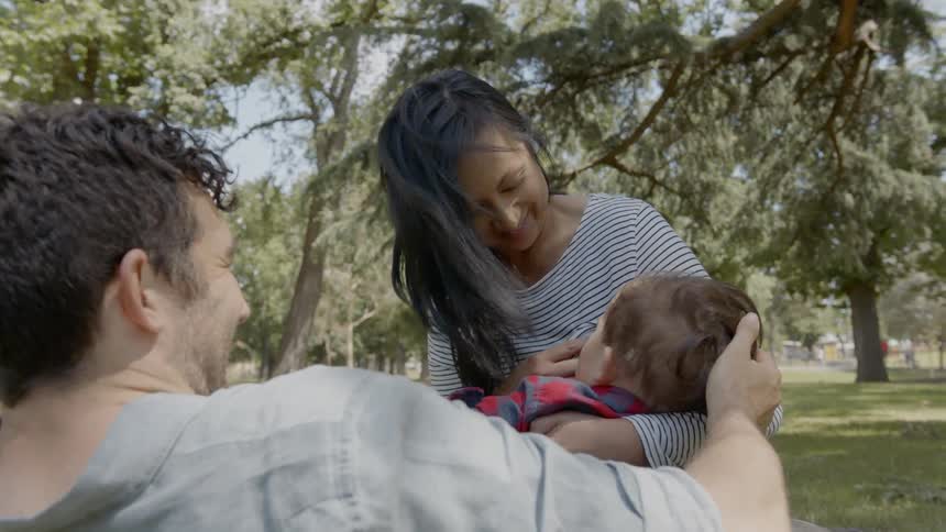 Parents hold their child sitting on a field