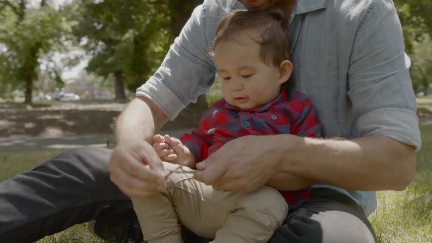 A man taps two little sticks together to amuse a toddler