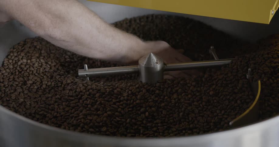 A person is moving coffee beans in a machine