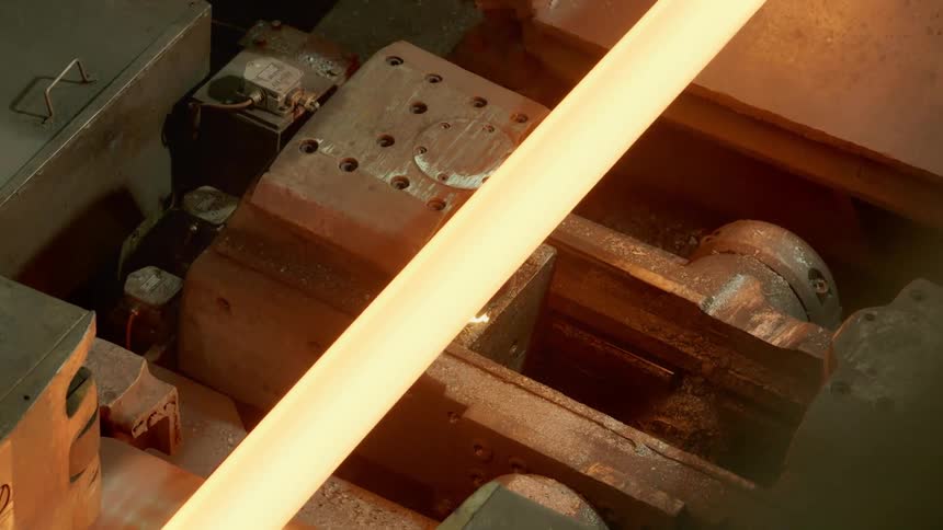 A molten piece of long metal slides over a mechanical device