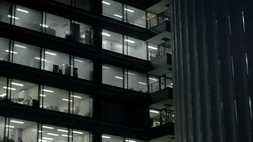 An office building at night with people walking around being busy