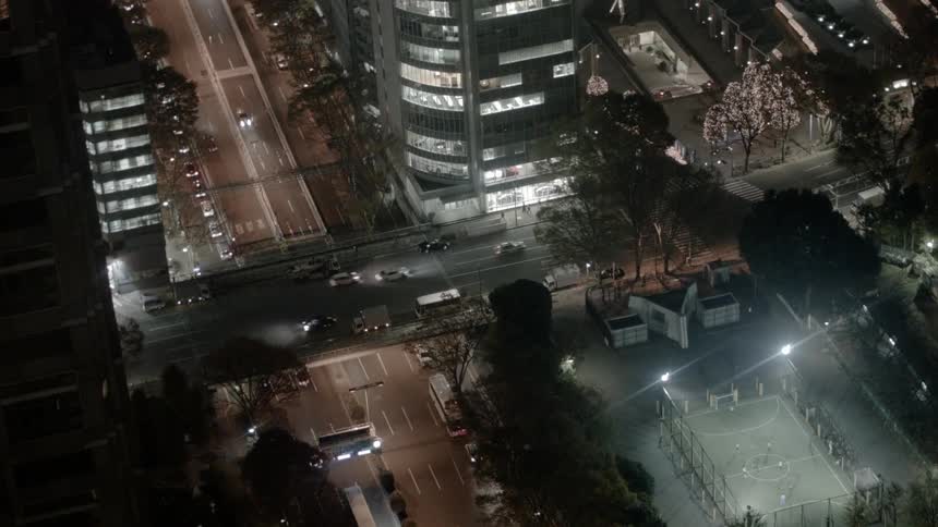Cars travel through a busy intersection and above it on a bridge in a large city