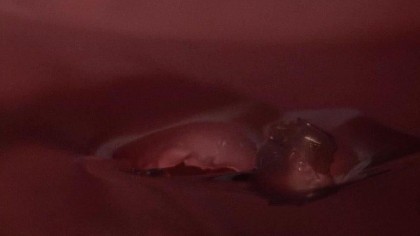A bubble pops in a thick red liquid