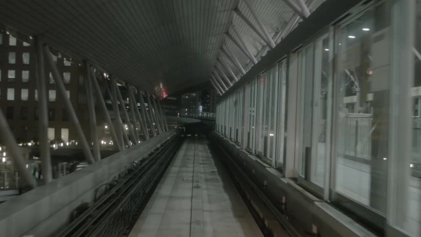 A passenger train travels on tracks through a city at night