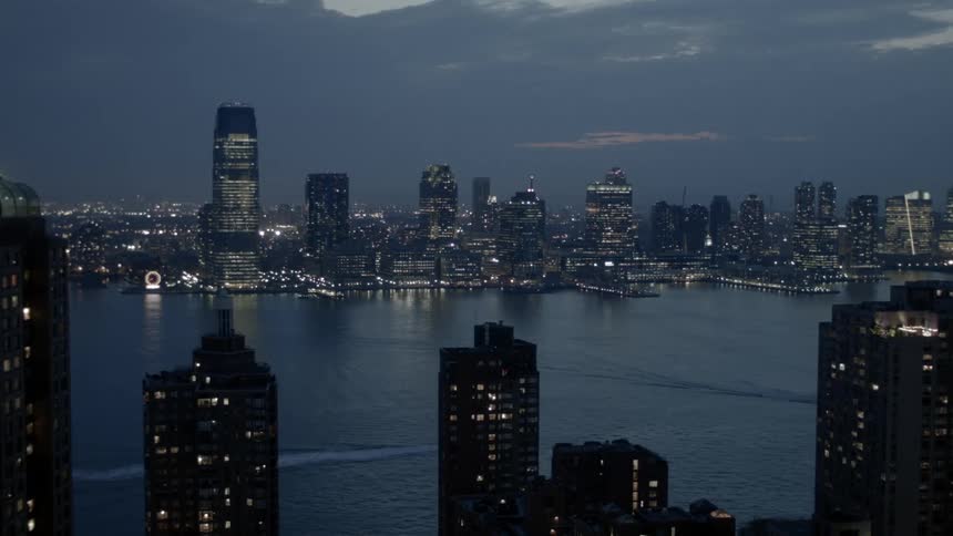 Boats in a lake with the city lit up behind it