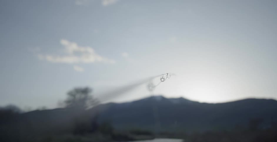 A fishing pole with the sky and mountains in the background