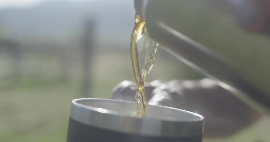 Coffee from thermos being poured on a cup outdoors