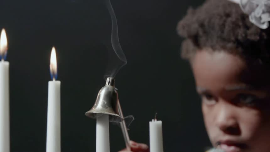 A young girl extinguishes a candle with a candle snuffer