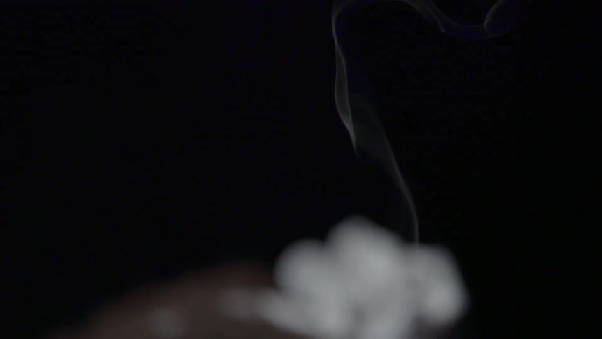 A young girl watches smoke from a candle