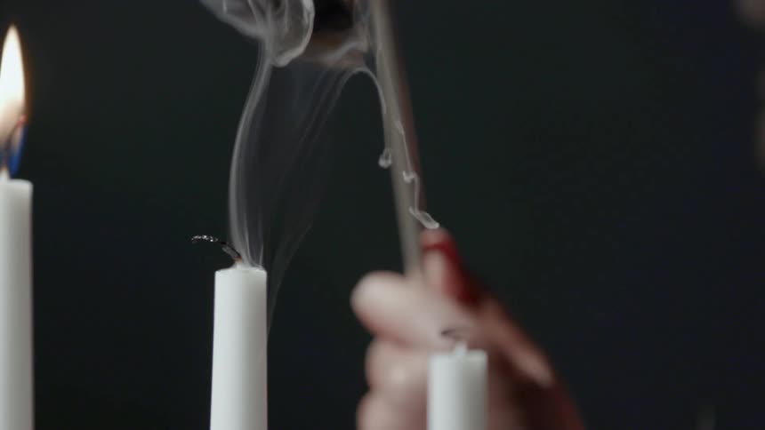 A woman extinguishing a white candle