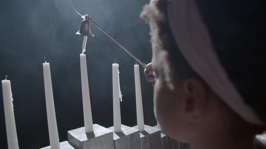 A young child extinguishes candles with a candle snuffer