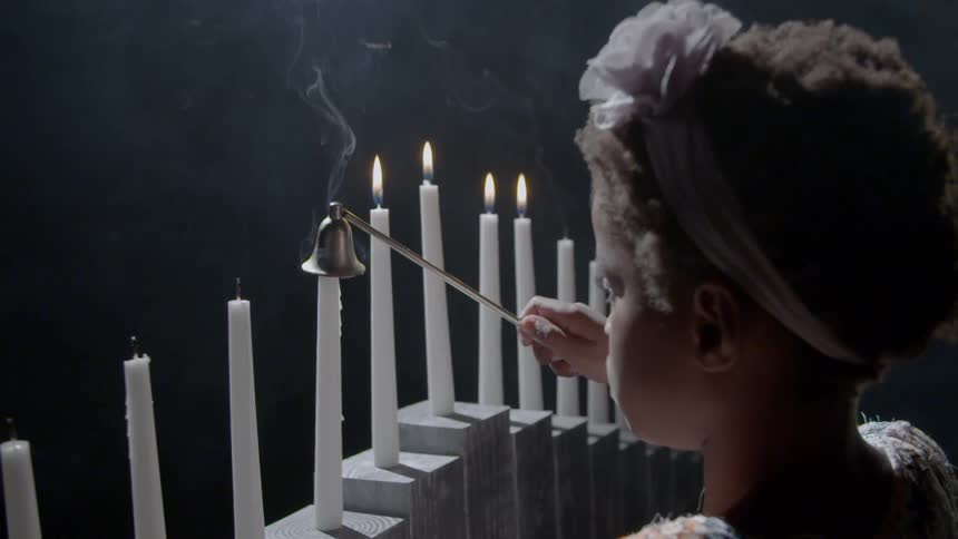 A girl is putting out candles in a dark area