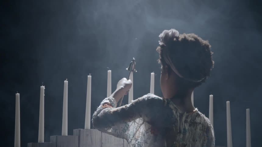 A young black girl snuffs out a candle flame