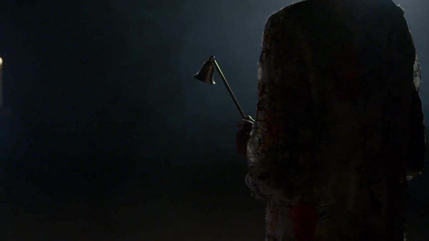 A woman walks with a candle snuffer