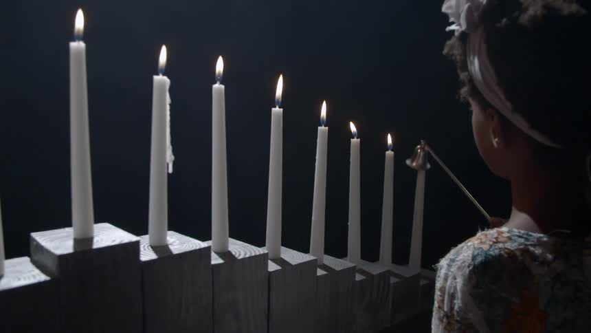 A young girl puts out a candle with a metal candle snuffer